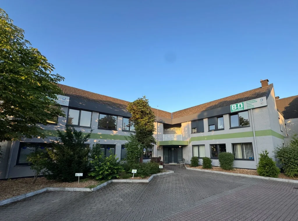 Contemporary office complex with gray facade, green horizontal stripe, large windows and paved parking lot